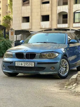 بي إم دبليو 116i موديل 2006 سيدان رمادية بفتحة سقف ومقاعد جلدية